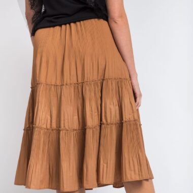 Vertical shot of a woman wearing a black shirt and a long beige skirt on a white background