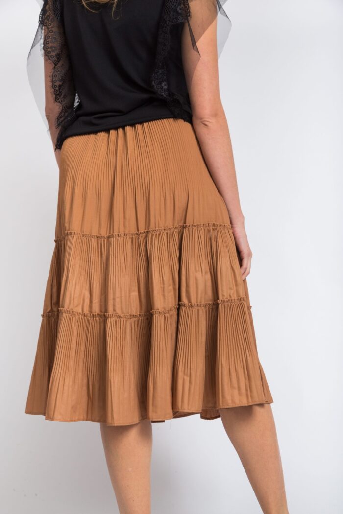 Vertical shot of a woman wearing a black shirt and a long beige skirt on a white background