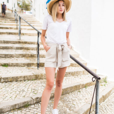 Pretty young girl in hat walks on the stair outdoors in summer street.