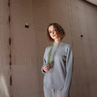 Young woman holding a fern leaf with a canvas backdrop