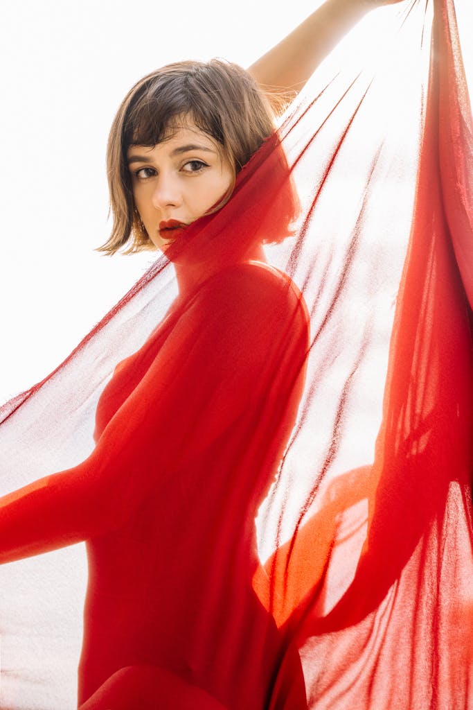 Captivating portrait of a woman in a red translucent fabric, highlighting elegance and beauty.