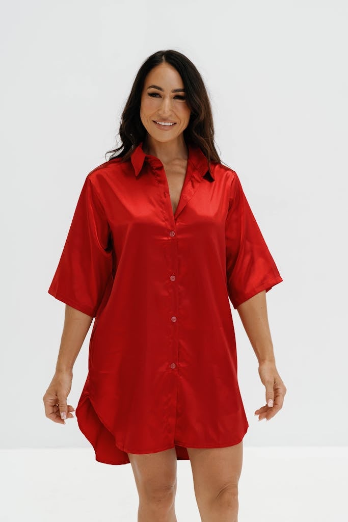 Confident woman wearing a vibrant red silk shirt dress, exuding elegance and modern fashion.