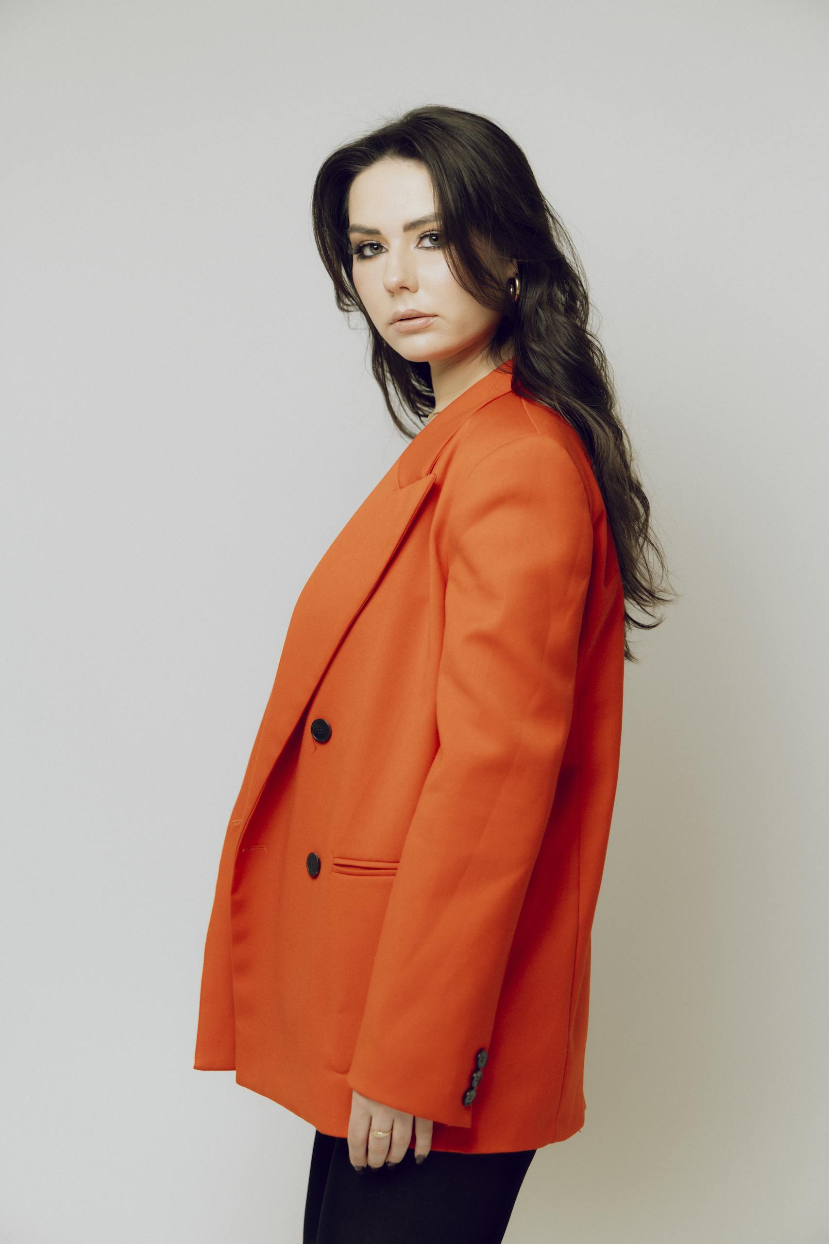 Stylish portrait of a woman in a vibrant red jacket, set against a clean white background.